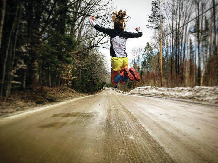 Jumping up in the air with energy during a run on a dirt road in Vermont, USA. skyrunning girl skyrunner skyracing skyrace naia tower-pierce